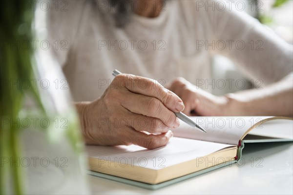 Hands of older woman writing in journal