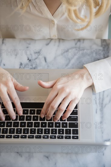 Hands of Caucasian woman typing on laptop
