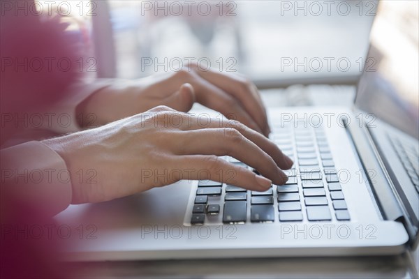 Hands of Caucasian woman typing on laptop
