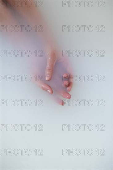 Hands of Caucasian woman in milk bath