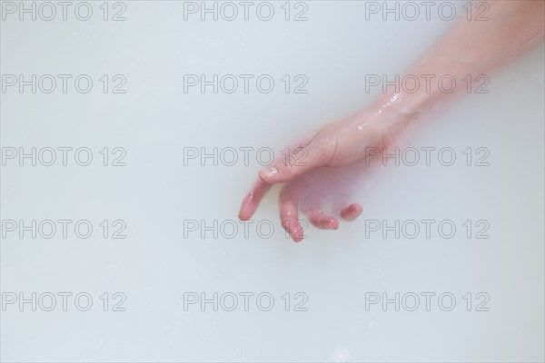 Hand of Caucasian woman in the milk bath