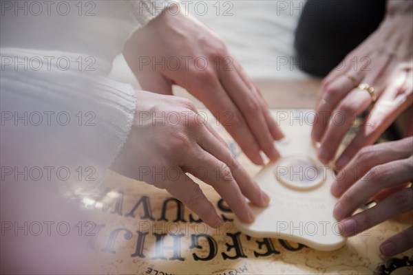 Hands of Caucasian women using a Ouija board