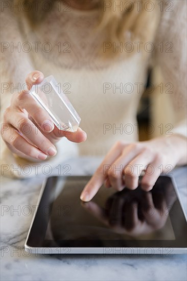 Caucasian woman holding crystal and using digital tablet