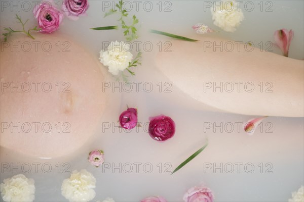 Caucasian expectant mother in milk bath with flowers