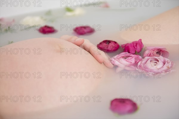 Caucasian expectant mother in milk bath with flowers