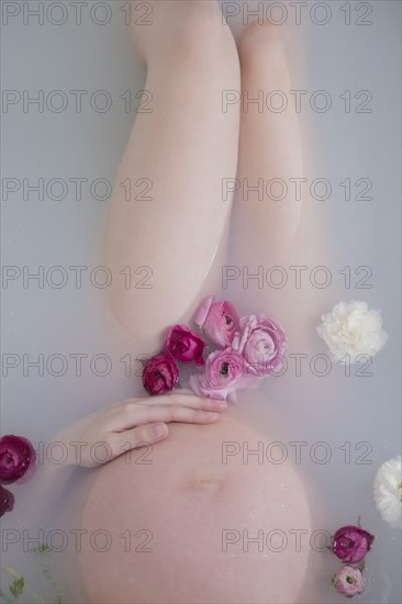 Caucasian expectant mother in milk bath with flowers