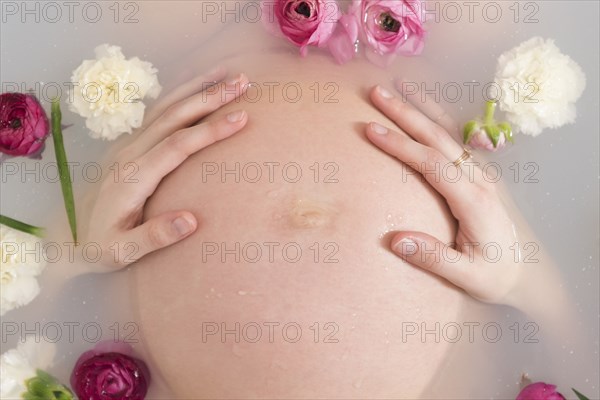 Caucasian expectant mother in milk bath with flowers