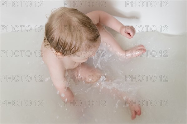 Caucasian baby boy splashing in the bathtub