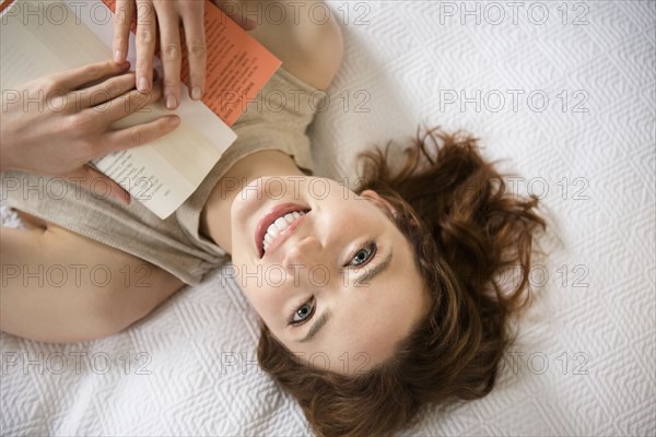 Caucasian woman laying on bed reading book