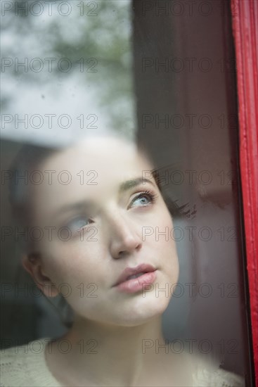 Caucasian woman daydreaming behind foggy window