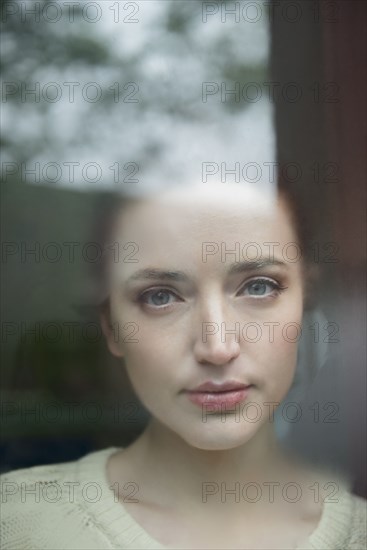 Serious Caucasian woman behind foggy window