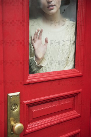 Caucasian woman daydreaming behind red door