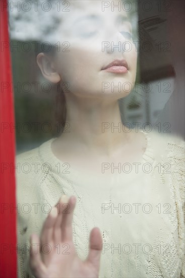 Caucasian woman daydreaming behind foggy window