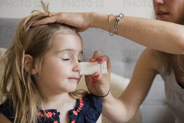 Caucasian mother applying sunscreen to face of daughter