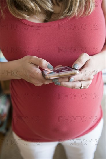 Caucasian expectant mother texting on cell phone