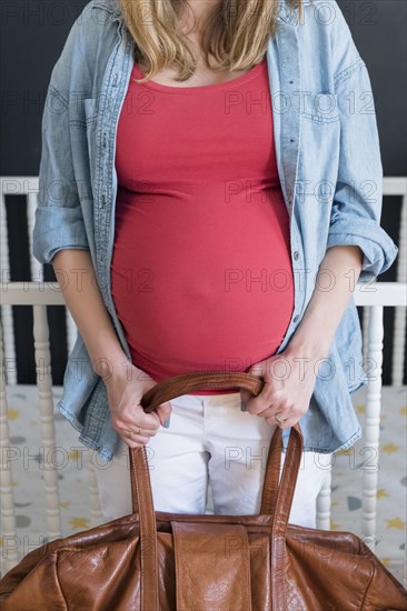 Caucasian expectant mother carrying bag