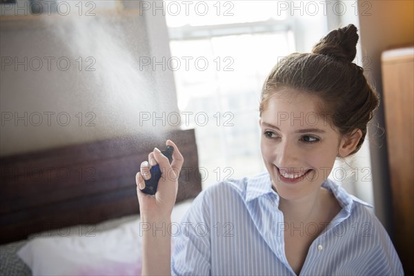 Caucasian woman spraying perfume in air