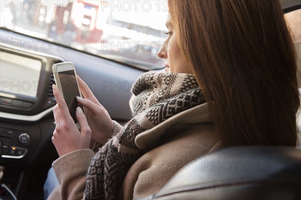 Caucasian woman sitting in car texting on cell phone