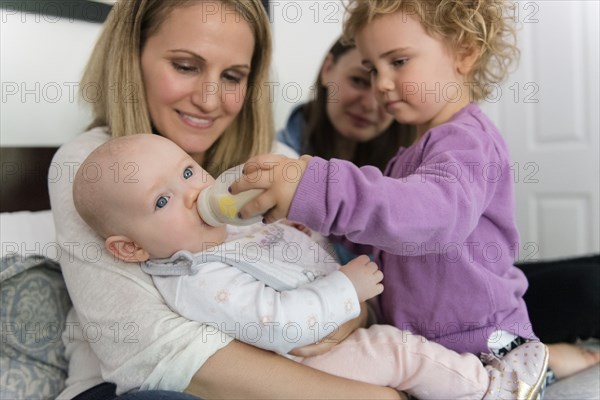 Caucasian girl feeding bottle to baby sister