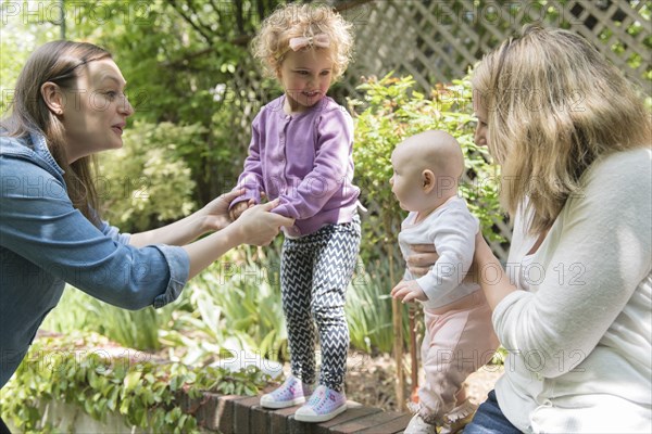 Caucasian mothers holding daughters on garden wall