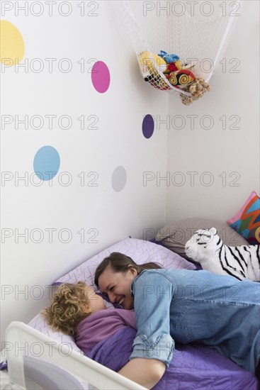 Caucasian mother and daughter laughing and cuddling in bed