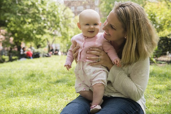 Portrait of Caucasian mother holding baby daughter in park