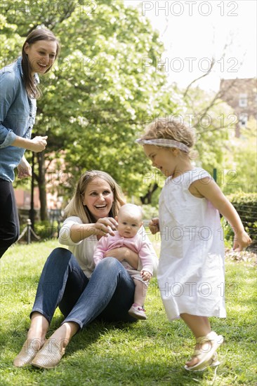 Caucasian mothers watching daughter running in park