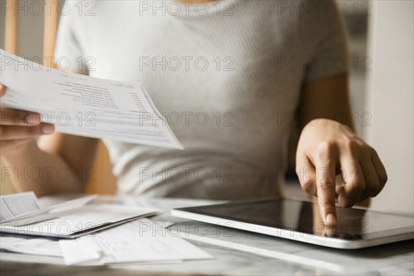 African American woman paying bills with digital tablet