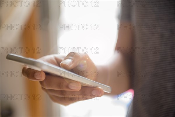 Hand of African American woman texting on cell phone