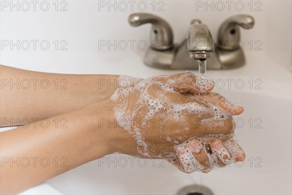 African American woman washing hands with soap