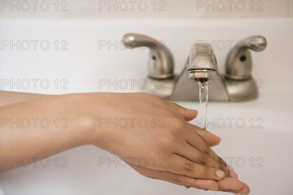 African American woman washing hands with water