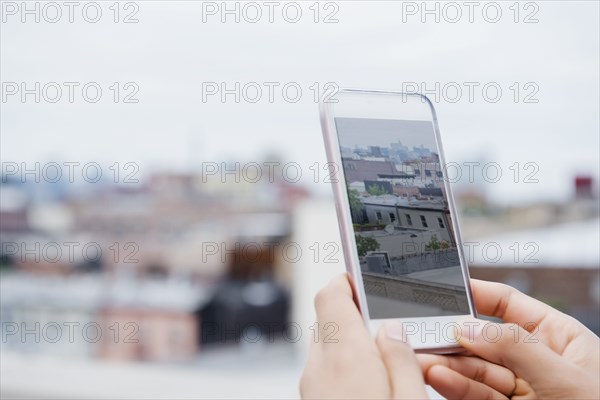 Hands of African American woman photographing cityscape with cell phone