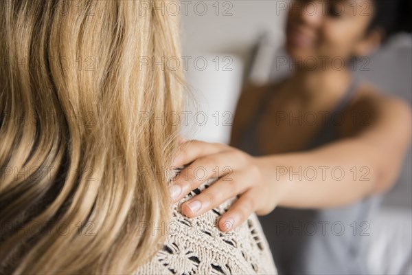 Woman comforting friend with hand on shoulder