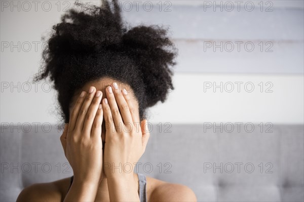 African American woman covering face with hands