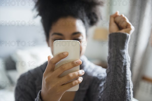 African American woman celebrating while texting on cell phone