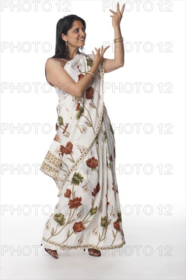 Smiling Indian woman in traditional clothing with arms raised