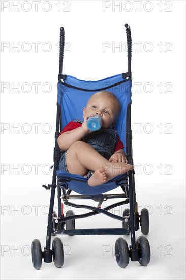 Caucasian baby boy in stroller drinking from bottle