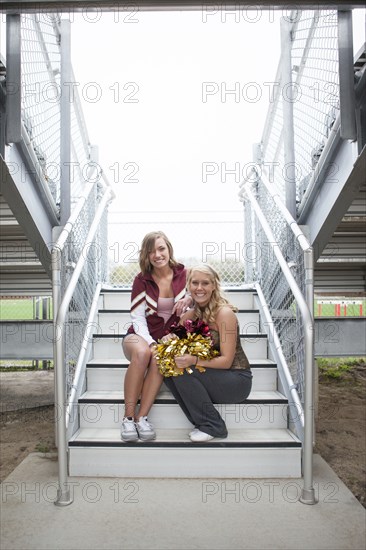 Caucasian cheerleaders smiling on bleacher stairs