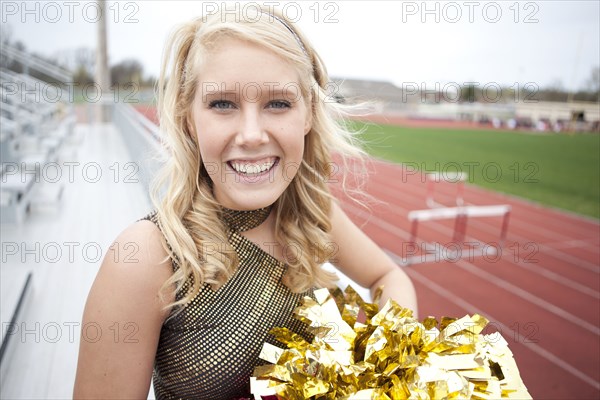 Caucasian cheerleader smiling on bleachers