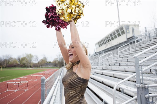 Caucasian cheerleader cheering on bleachers