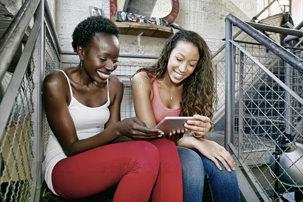 Women using digital tablet on steps