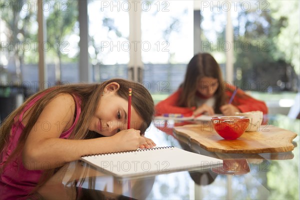 Mixed race sisters doing homework at table