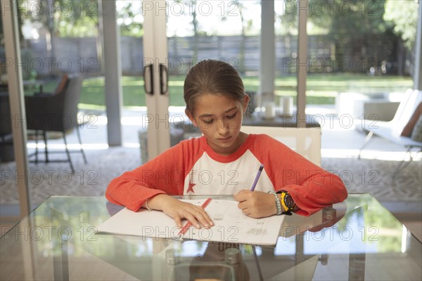 Mixed race girl doing homework at table