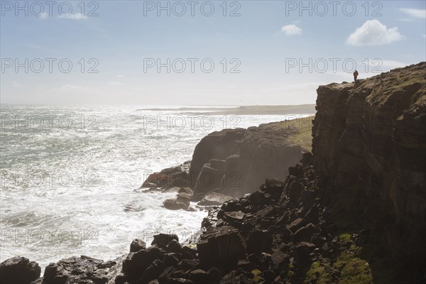 Chinese man standing on cliff at ocean