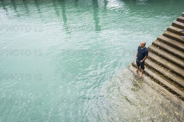 Chinese man standing on staircase in water