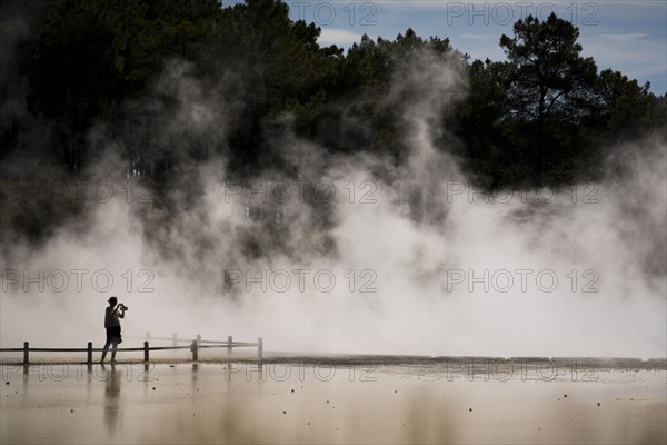 Distant Caucasian woman photographing geothermal pool