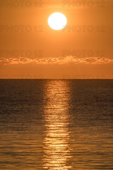 Blazing sunrise in orange sky over ocean