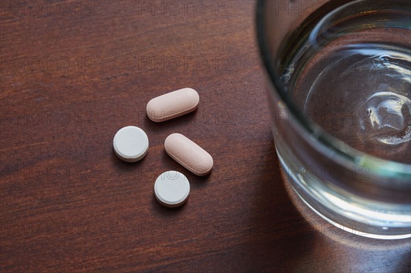 Overhead view of glass of water and pills on table