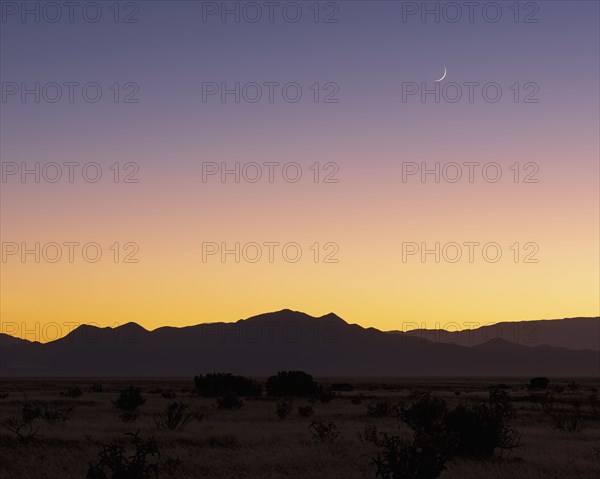 Crescent moon above Jemez Mountains at sunset