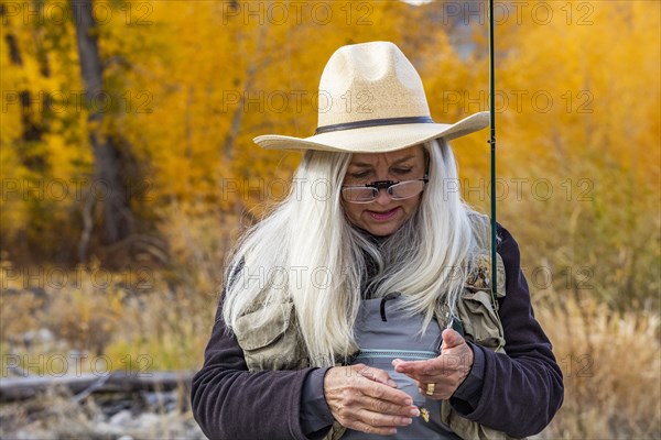 Senior woman putting bait on fishing rod